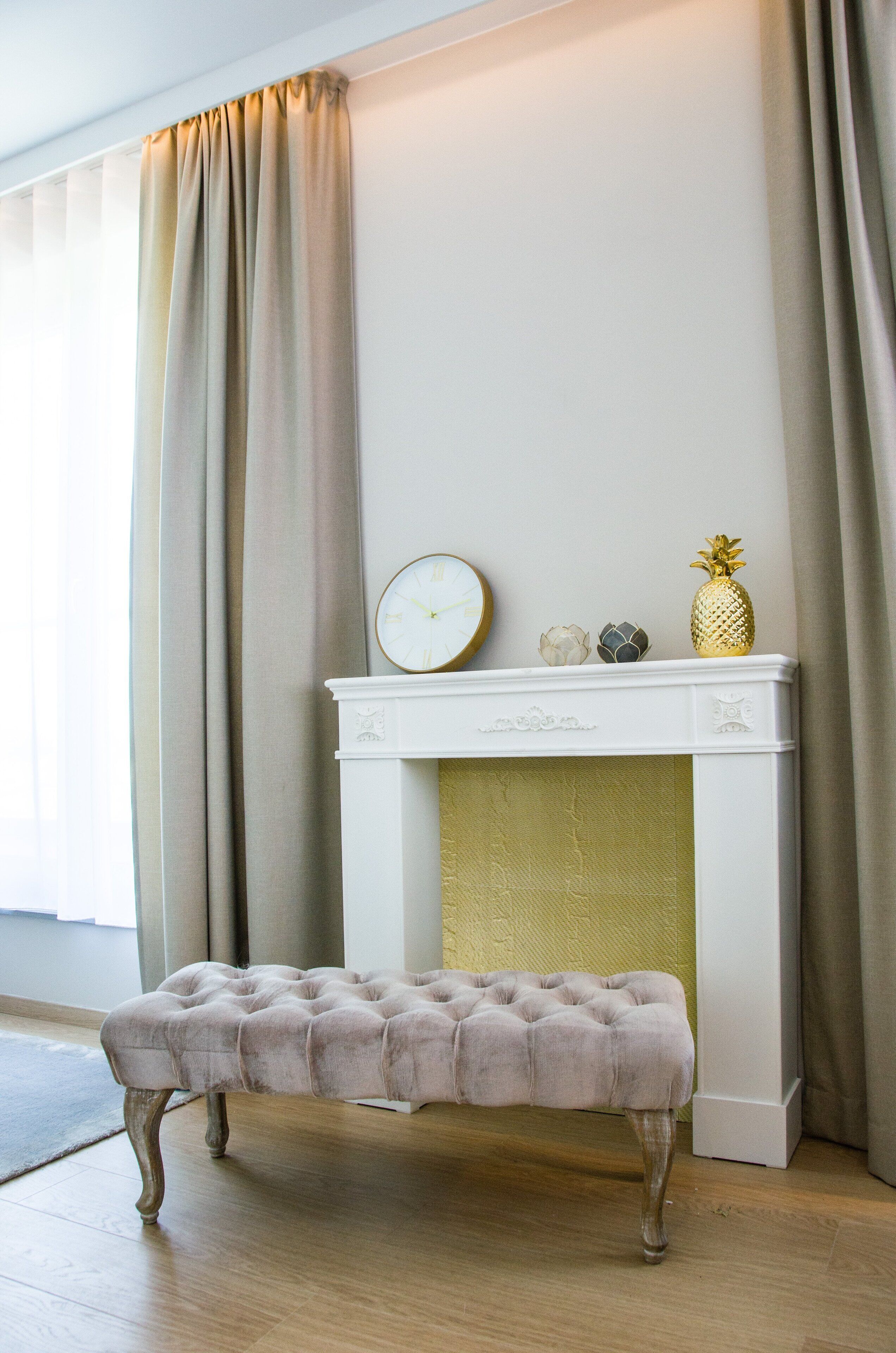 A room with a white fireplace, a clock, and a pineapple decoration.