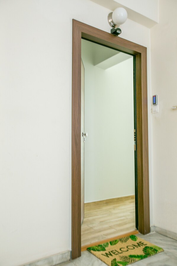 Una porta con stipite in legno, un tappetino d'ingresso e un lampadario sopra.