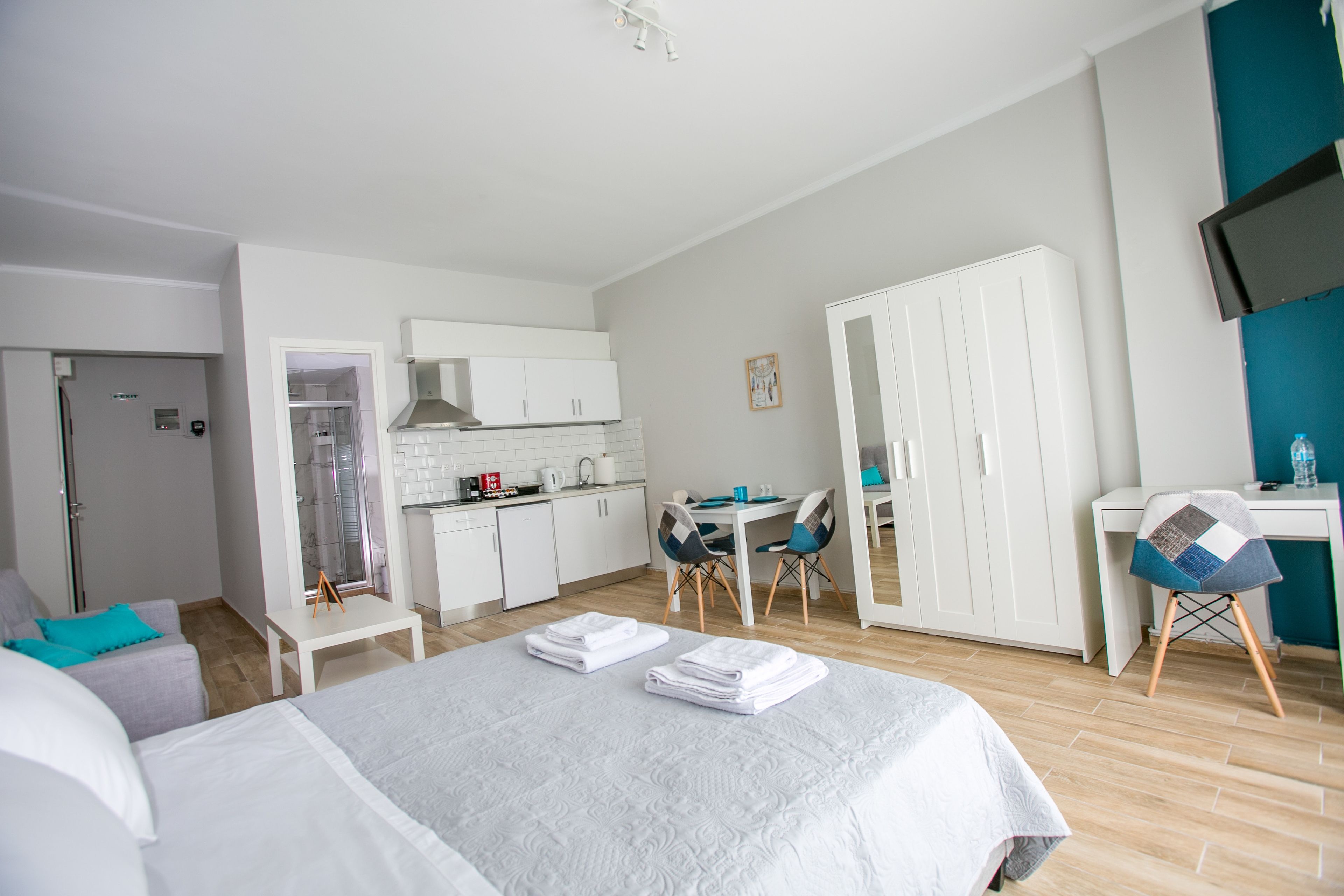Et hotelværelse med seng, skrivebord, stol, garderobeskab og tekøkken.