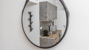 A modern kitchen with a round mirror, grey cabinets, a wooden countertop, and a coffee machine. - Raise comfy studios in the heart of Athens (Athens)