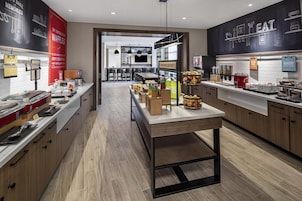 Una cocina moderna con una isla central, asientos tipo bar y una variedad de alimentos a la vista.
