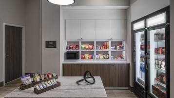 A kitchenette with a microwave, coffee machine, and a refrigerator.