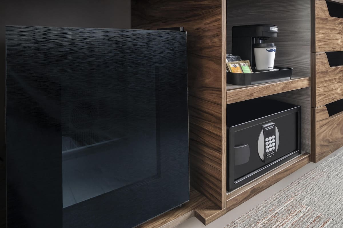 A modern kitchen with a black refrigerator, a coffee machine, and a built-in safe.