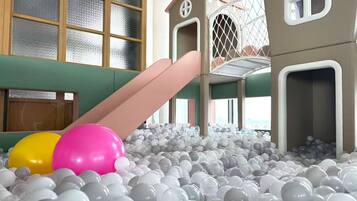 Un área de juegos con una piscina de pelotas, un tobogán y una estructura para escalar.