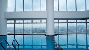 An indoor infinity pool with a city view through large windows.