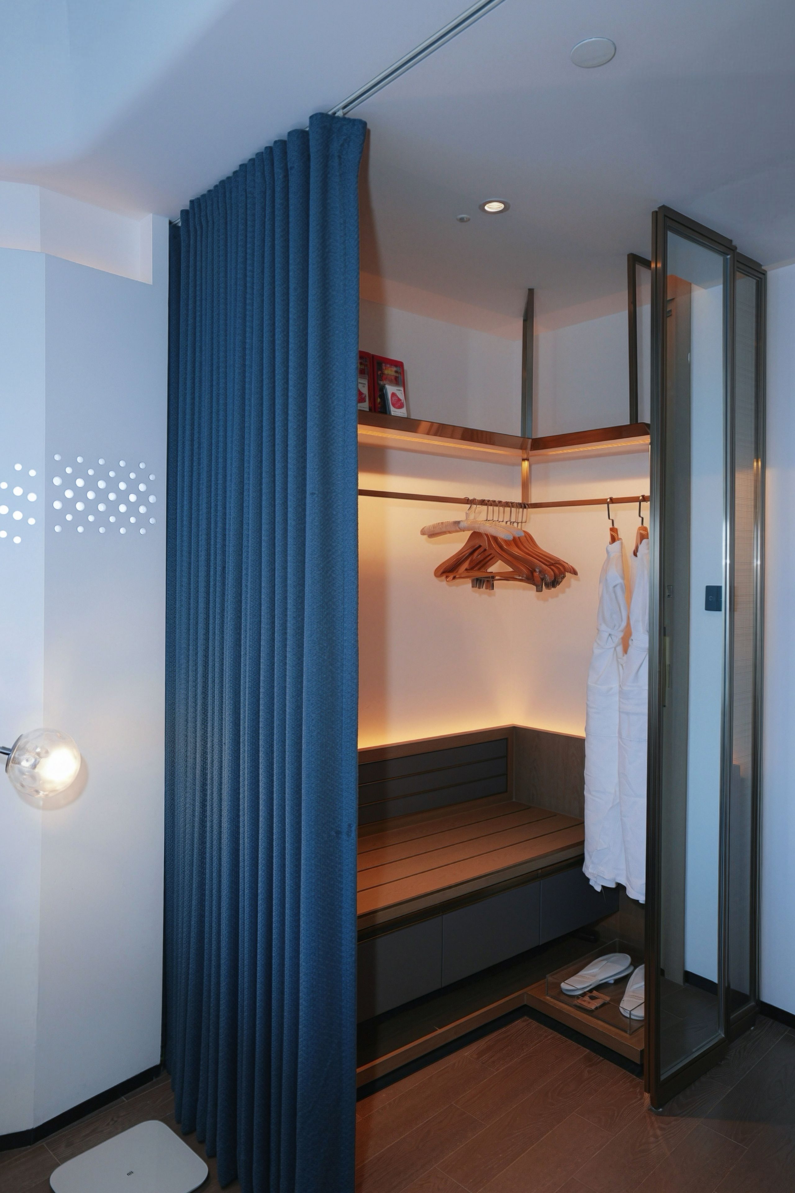 A modern bathroom with a built-in bench, a glass shower enclosure, and a hanging robe rack.
