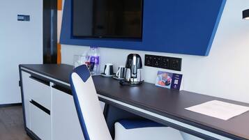 A modern office space with a desk, chair, and a large flat-screen TV mounted on the wall.