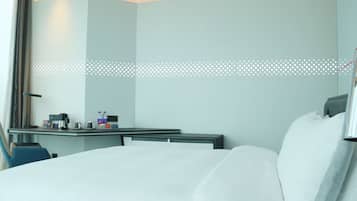 A hotel room with a bed, bedside table, and a desk with a chair.