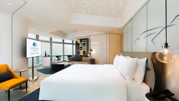 A modern hotel room with a large bed, a desk, a chair, and a TV displaying the DoubleTree logo.