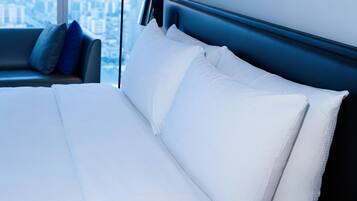 A modern hotel room with a large bed, a view of the city, and a cityscape visible through the window.