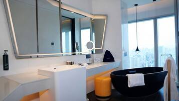 A modern bathroom with a large mirror, a black bathtub, and a city view.