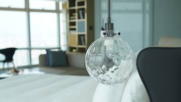 A modern bedroom with a large bed, a glass pendant light, and a bookshelf in the background.