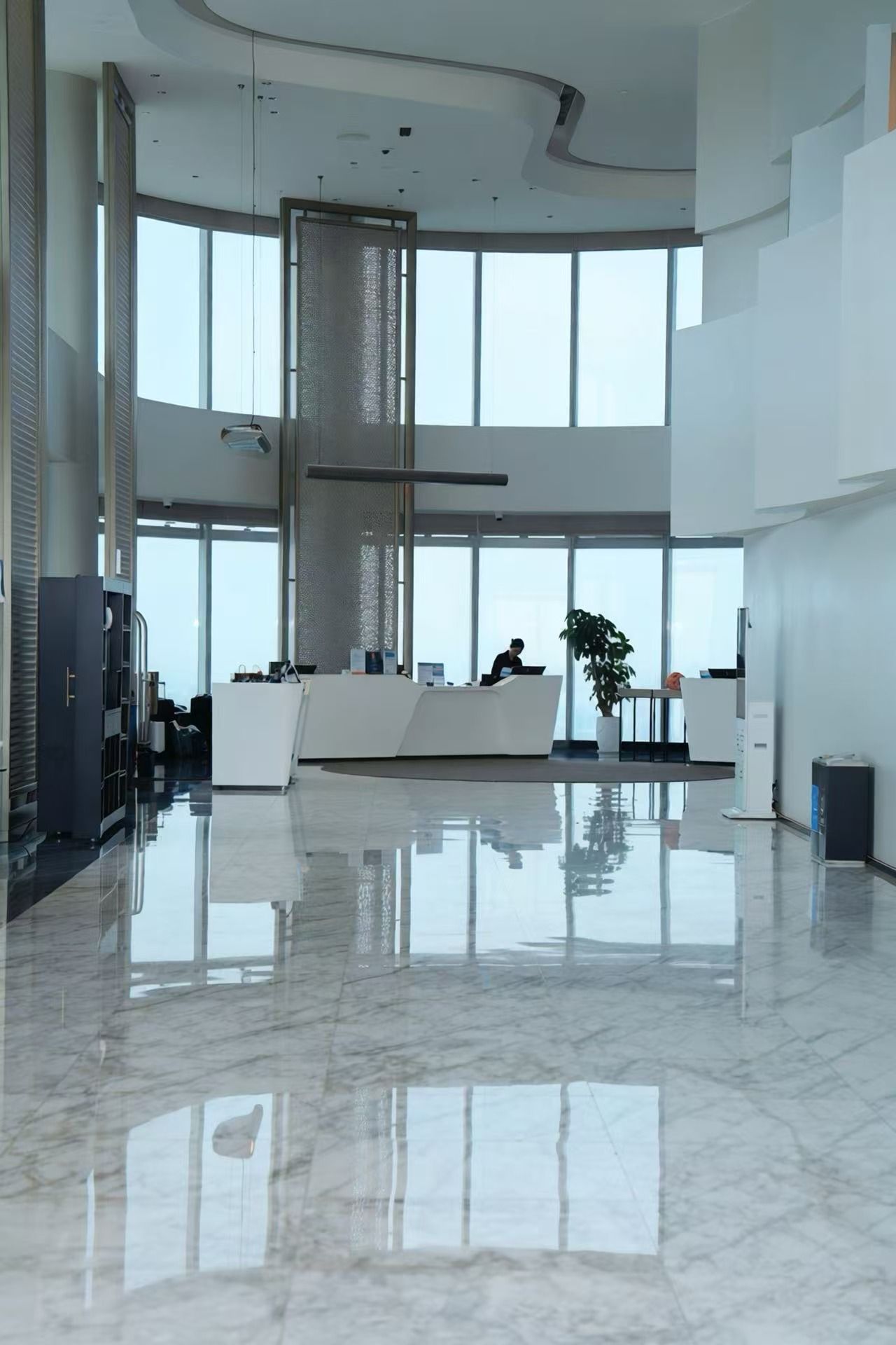 A spacious lobby with a reception desk, seating area, and large windows.