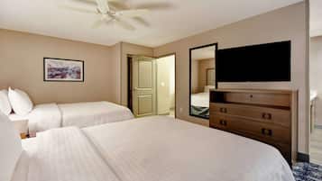 Habitación de hotel con dos camas, un ventilador de techo, un televisor de pantalla plana, un aparador y una puerta que da a otra habitación.