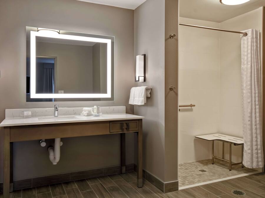 A modern bathroom with a large mirror, vanity, and a shower area.