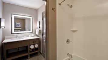 A modern bathroom with a large mirror, a sink, a shower, and a toilet.