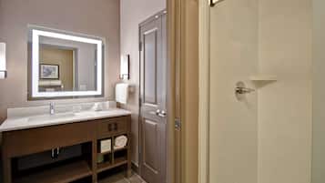 Un baño moderno con un espejo grande, un lavabo y una zona de ducha.