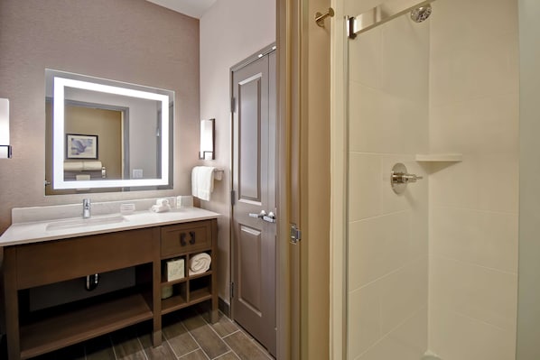 A modern bathroom with a large mirror, a sink, and a shower area.