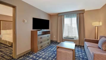 Une chambre d’hôtel équipée d’un lit, d’une télévision, d’un bureau, d’un canapé et d’une fenêtre avec des rideaux.