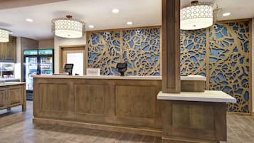 Zona de recepción con mostrador de madera, minibar y un panel decorativo con diseños elaborados.