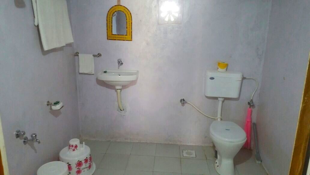 A small bathroom with a toilet, sink, and a mirror.