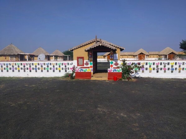 Un petit bâtiment doté d’un toit en tuiles, entouré d’un mur blanc orné de motifs colorés.