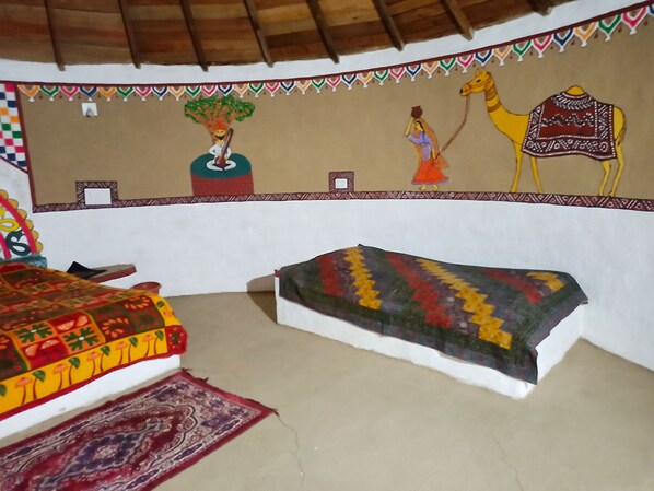 A room with a bed, a small table, and a wall mural.