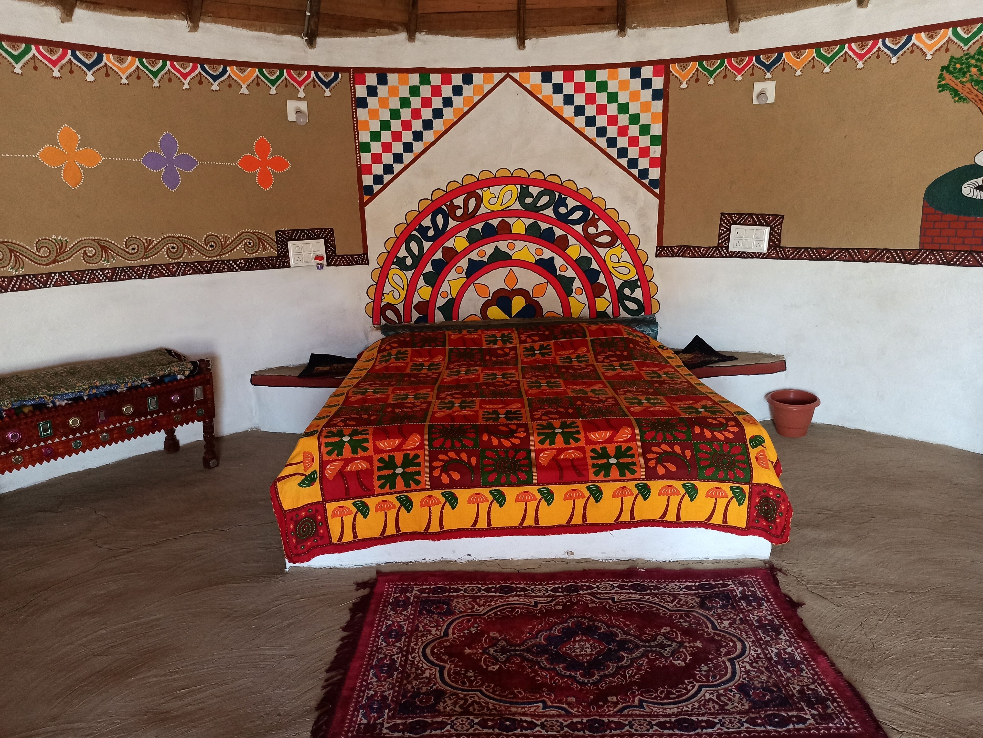A traditional room with a bed, a bench, and a patterned wall.