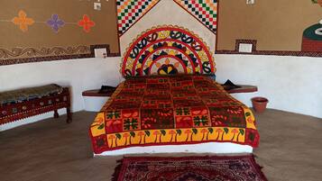 A traditional room with a bed, a bench, and a patterned wall.