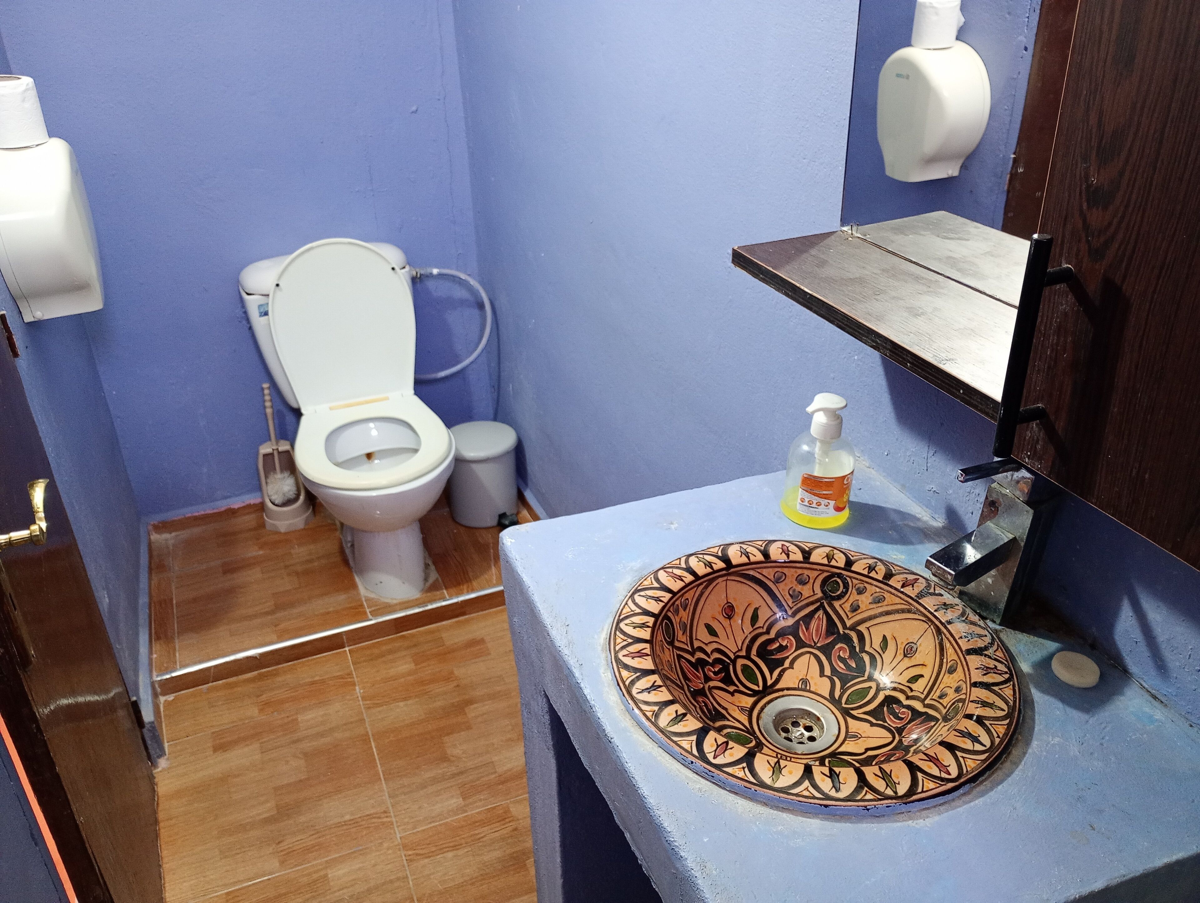 Een badkamer met toilet, een wastafel met decoratieve wasbak en een zeepdispenser.