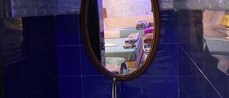 A bathroom with a mirror, sink, and blue-tiled walls.