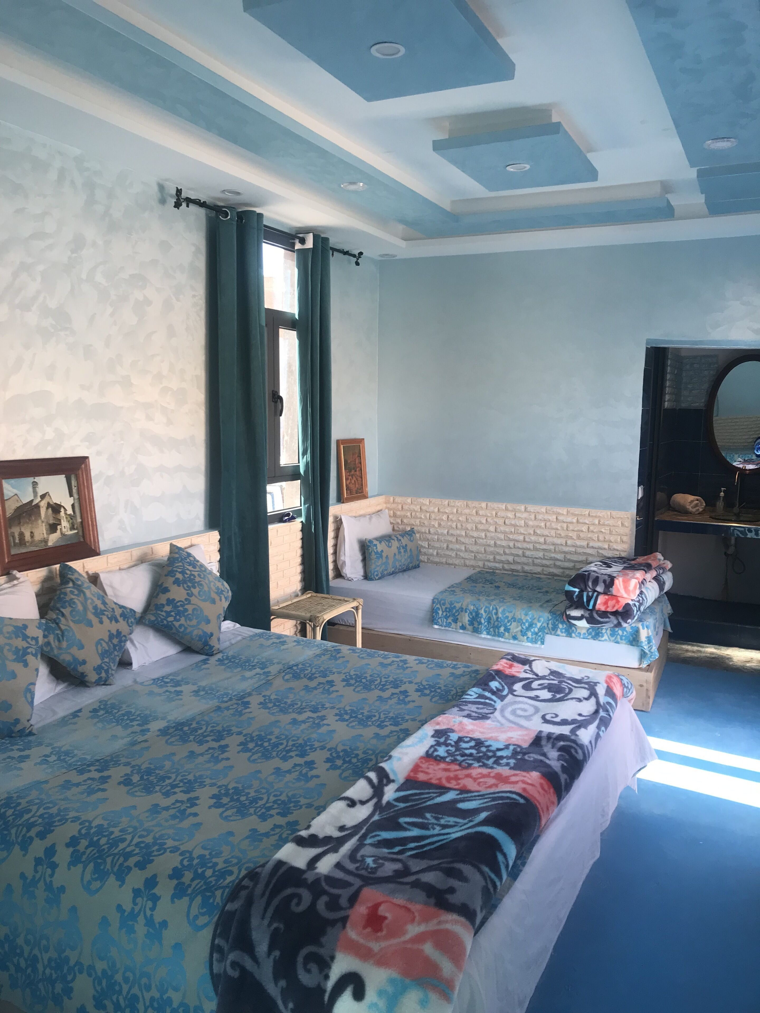 Un dormitorio con dos camas, un espejo grande y una ventana con cortinas.