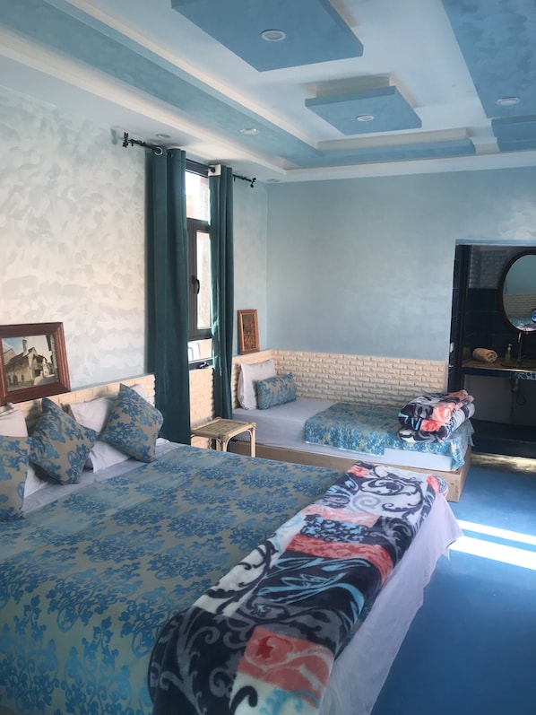 Un dormitorio con dos camas, un espejo grande y una ventana con cortinas.