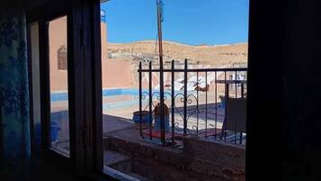 A view from a window with a metal railing, a pool, and a desert landscape.