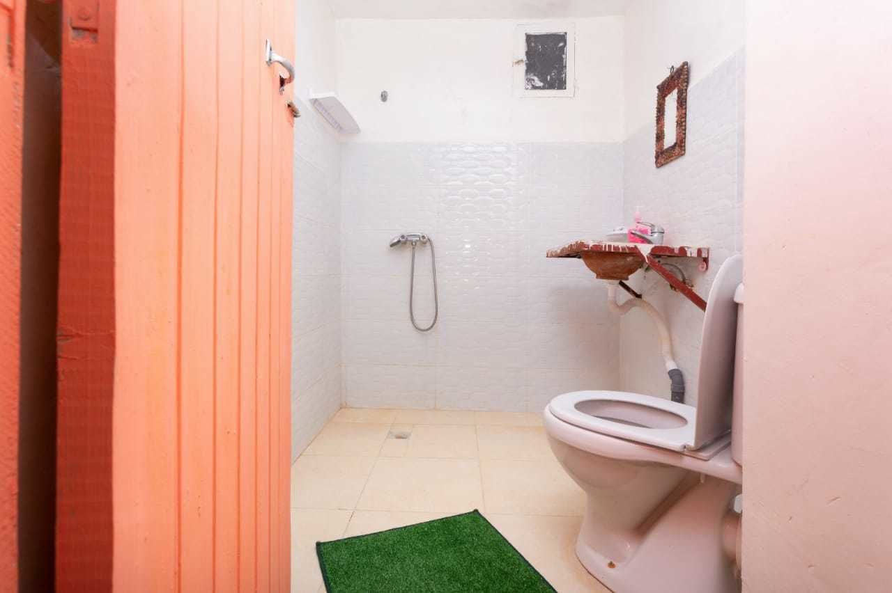 Une petite salle de bain compacte, équipée de toilettes, d’une douche et d’un lavabo.