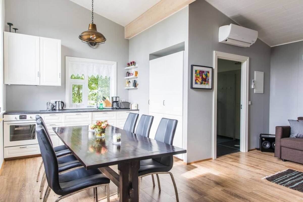 A modern kitchen with white cabinets, a dark wooden dining table, and a black chair.