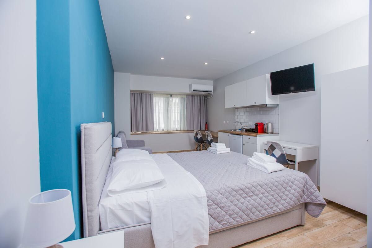 Una habitación de hotel moderna con una cama grande, un escritorio, un televisor de pantalla plana y una ventana con cortinas.