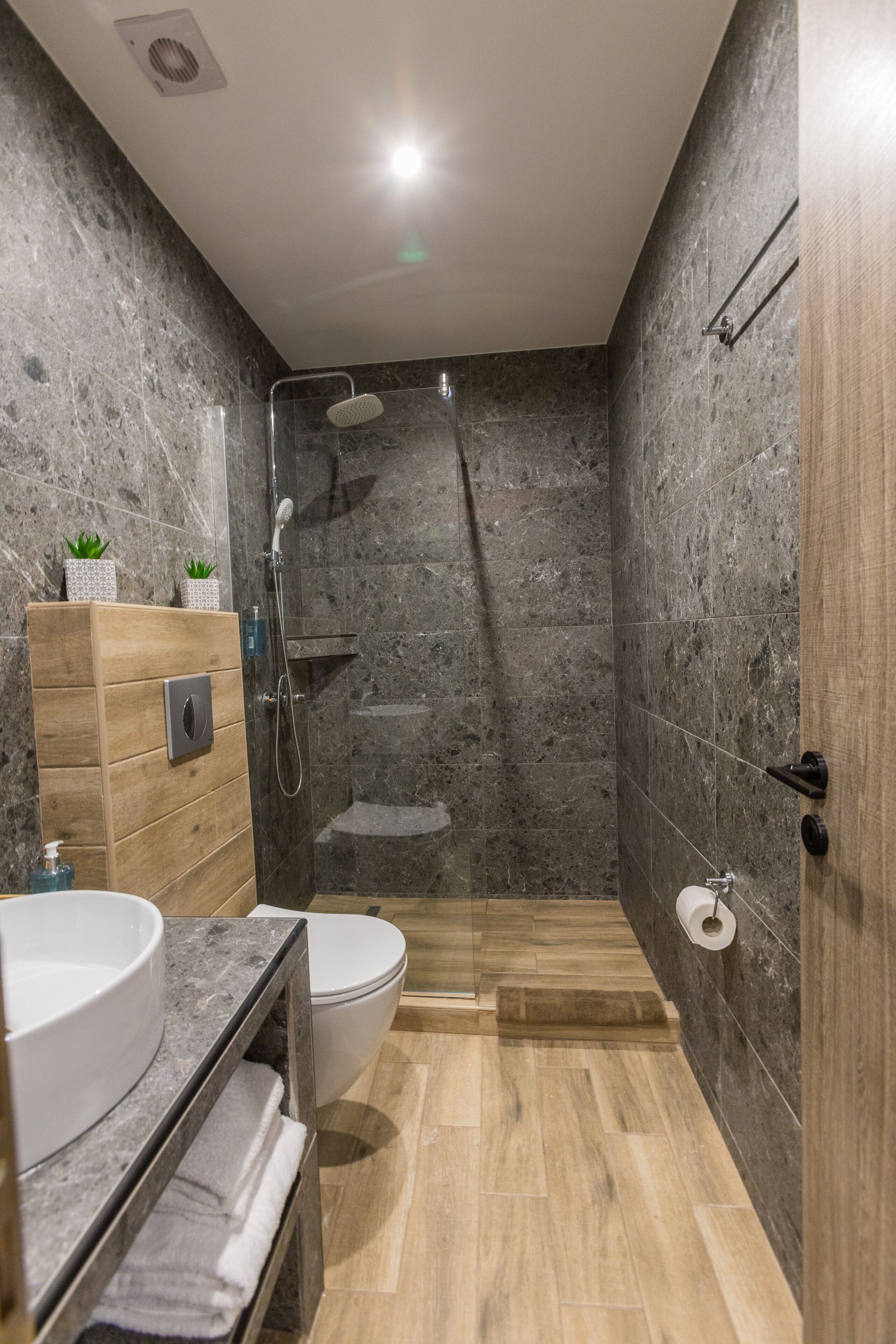 A modern bathroom with a shower, toilet, and vanity.