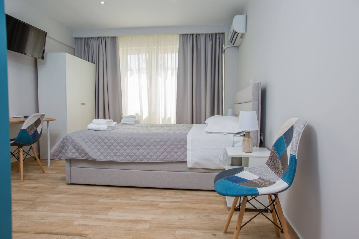 Una habitación de hotel con una cama, un escritorio, una silla y un televisor.