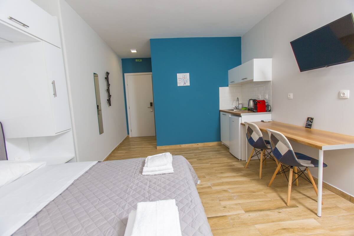 Habitación de hotel con cama, escritorio y kitchenette.