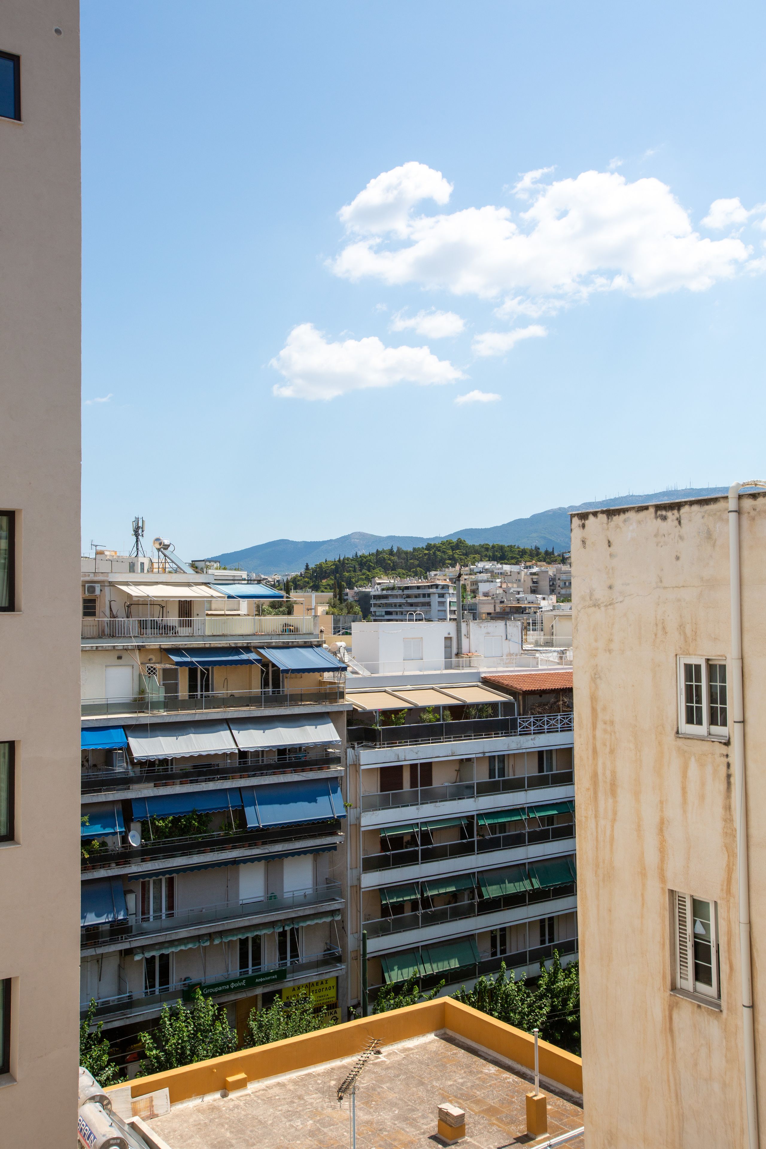 A multi-story building with balconies, a rooftop terrace, and a view of a mountain in the distance.