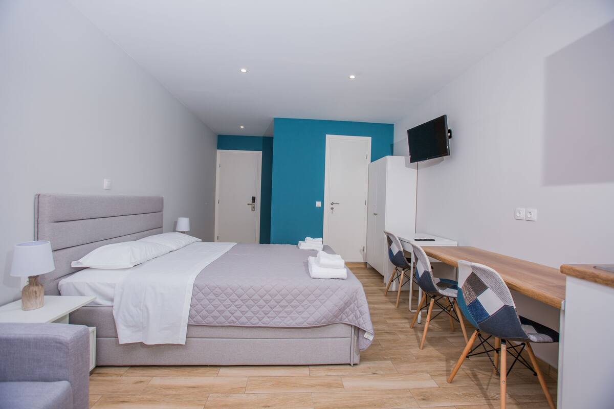 Un dormitorio moderno con cama, mesita de noche, lámpara y escritorio con sillas.
