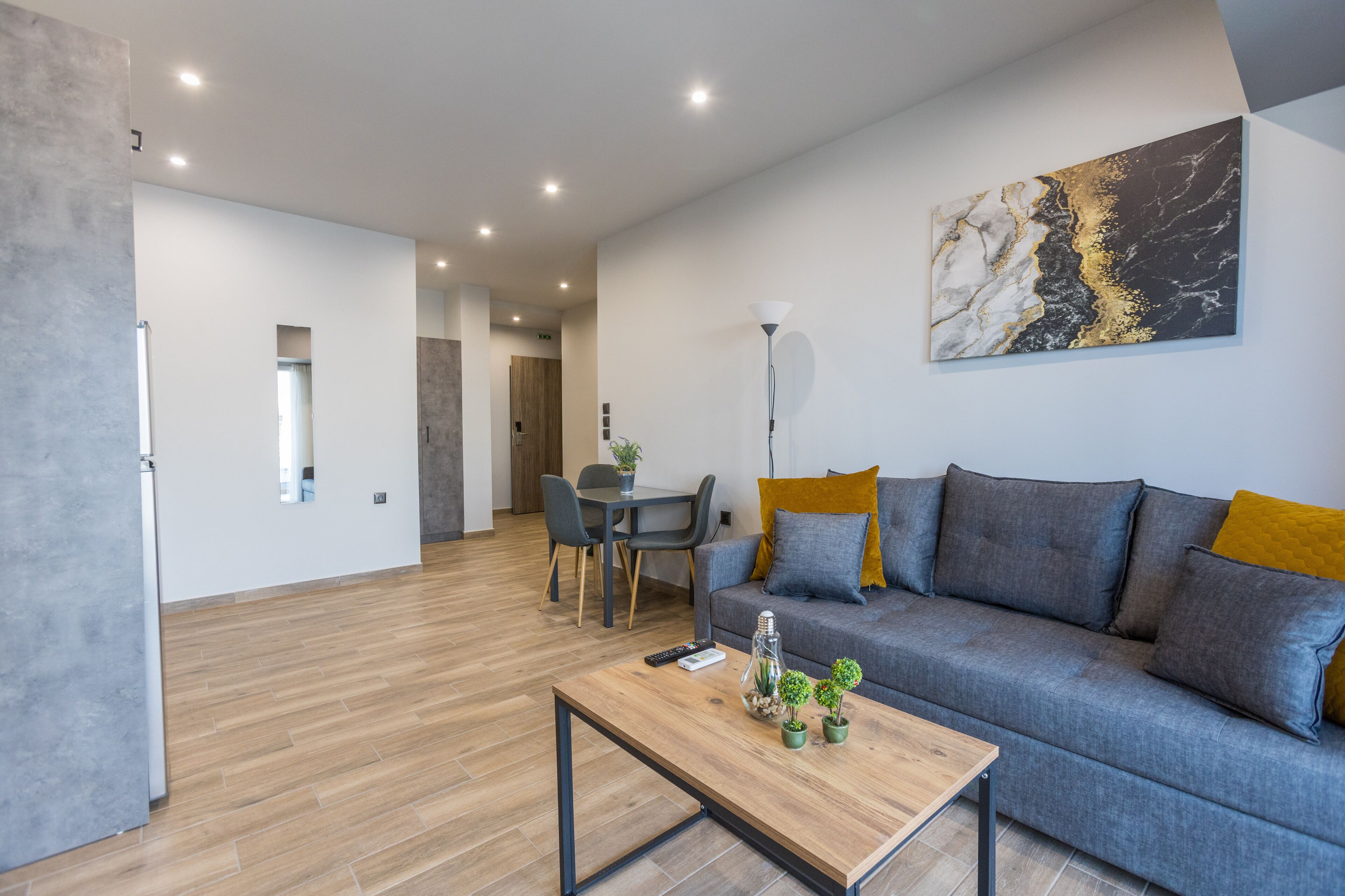A modern living room with a grey sofa, wooden coffee table, and a painting on the wall.
