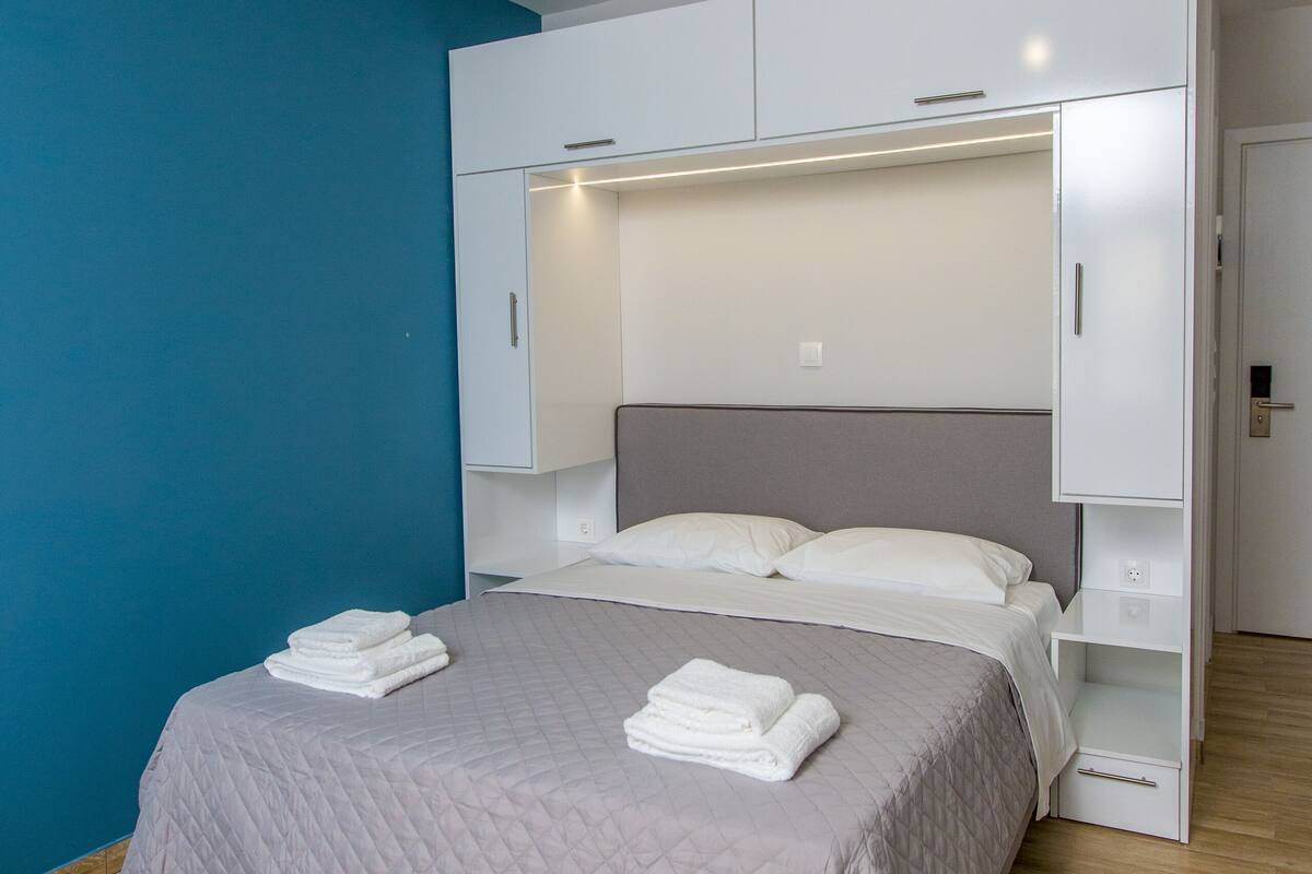 Un dormitorio moderno con cama, armario empotrado y pared azul de acento.
