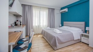 Una habitación de hotel moderna con cama, escritorio, silla y kitchenette.