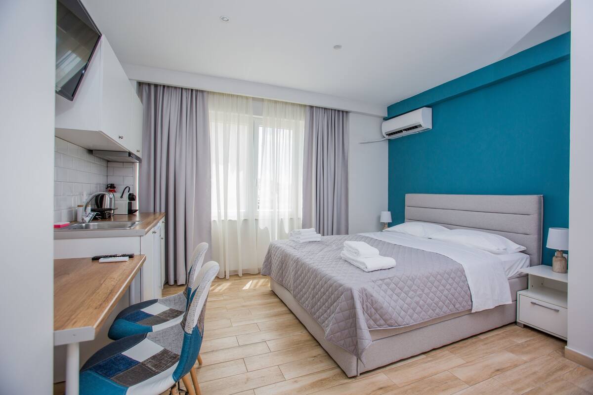 Una habitación de hotel moderna con cama, escritorio, silla y kitchenette.