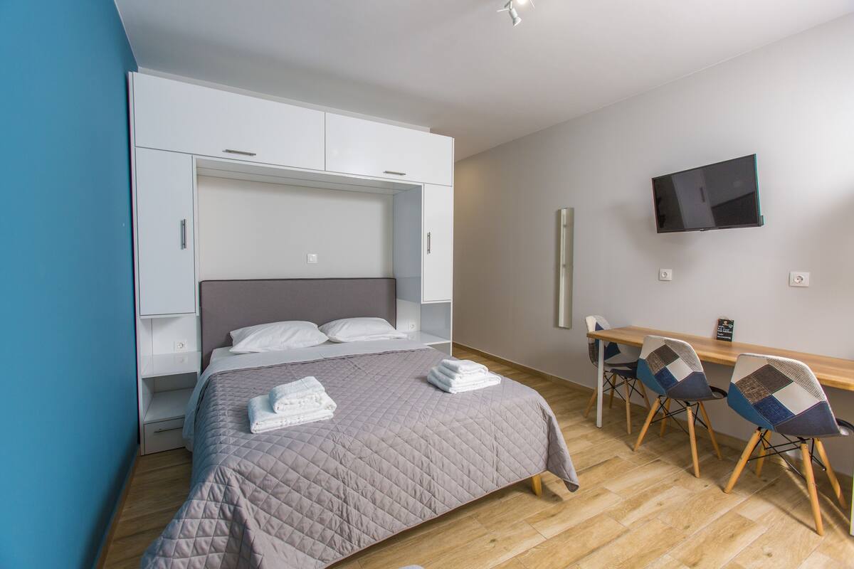 Un dormitorio con cama, escritorio, sillas y televisor.