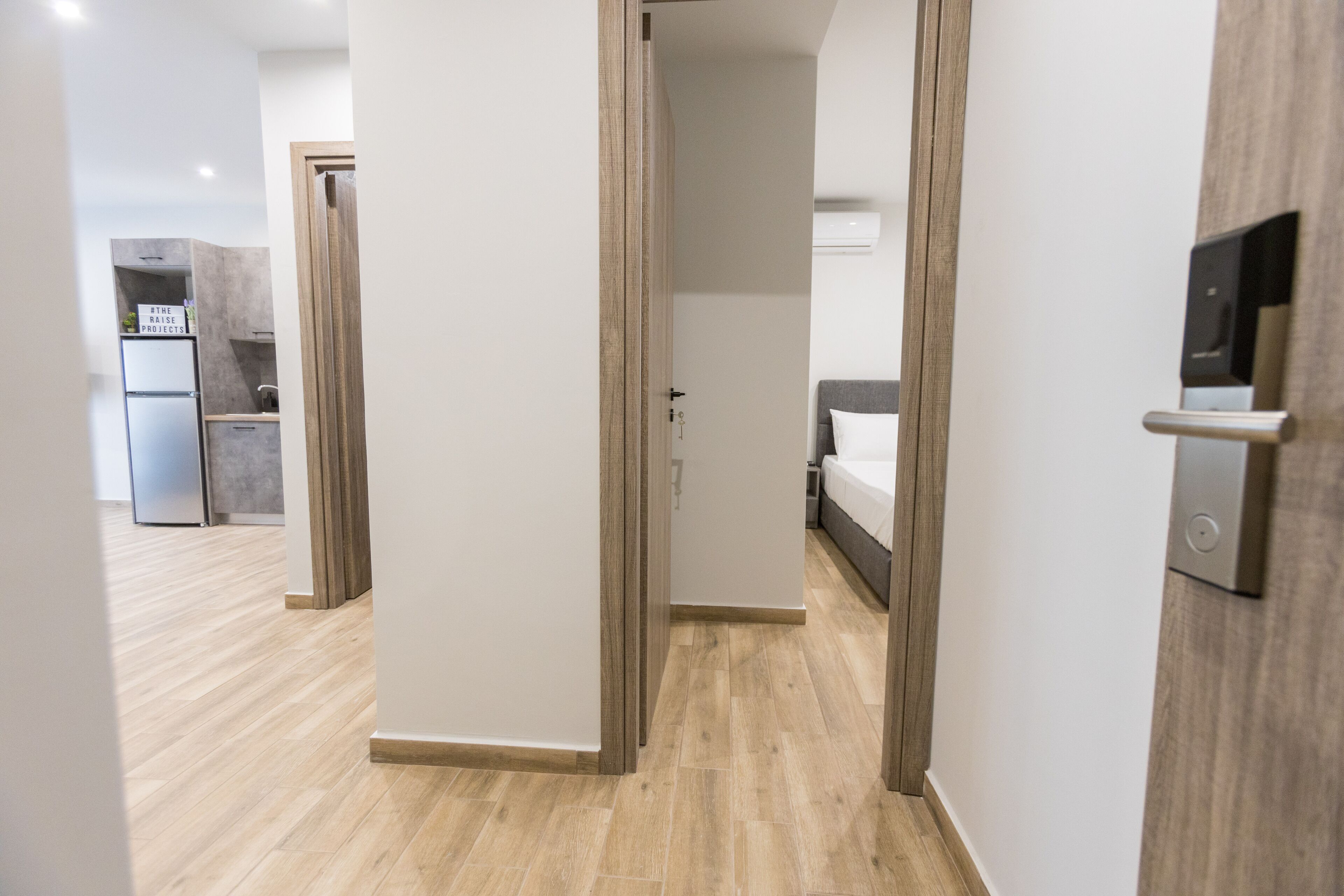 Ein modernes Hotelzimmer mit Holzboden, einem Bett, einem Nachttisch und einem fest installierten Fernseher.