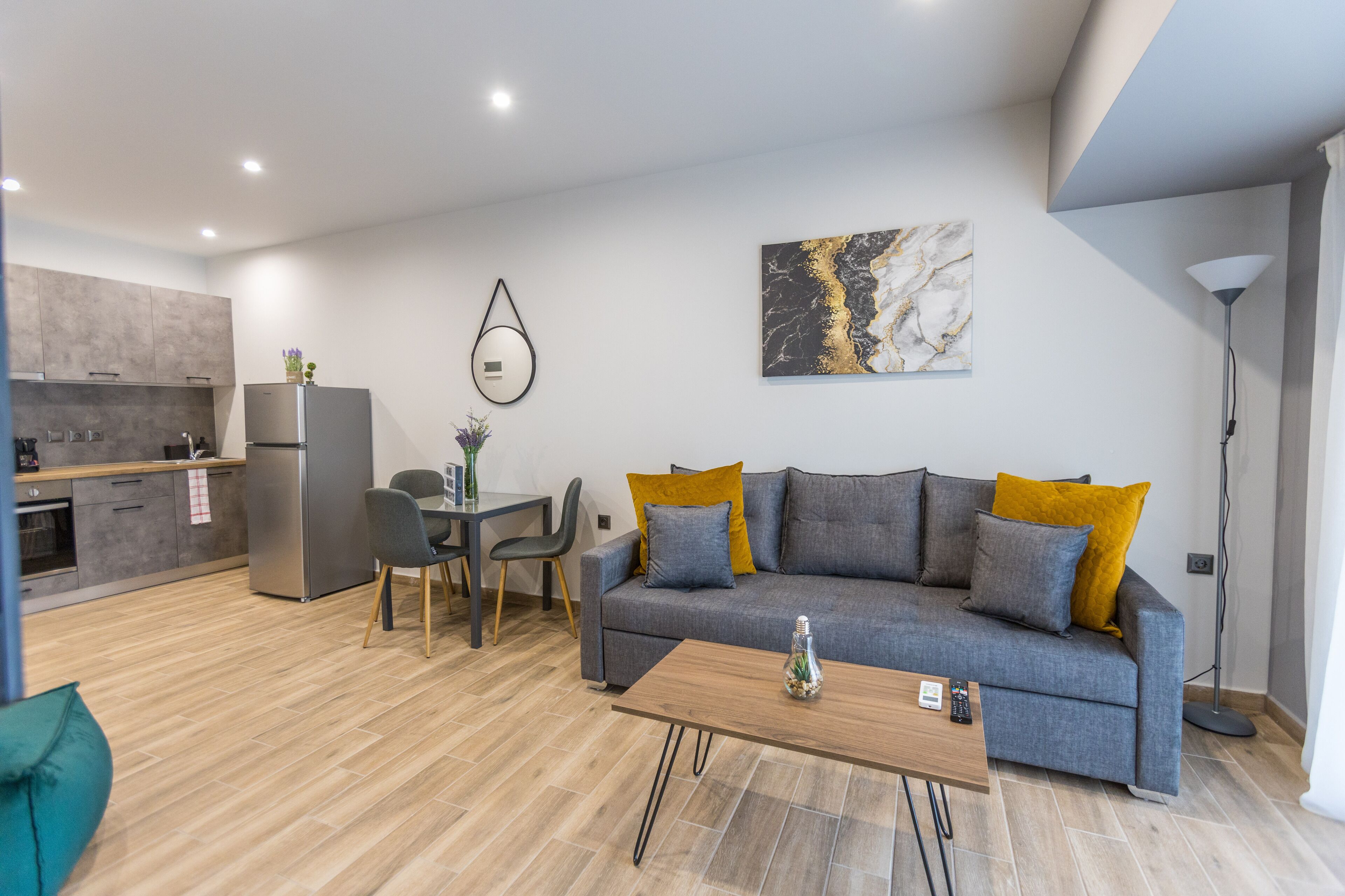 A modern living room with a grey sofa, wooden coffee table, and a dining area with a small table and chairs.