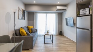 Una sala de estar moderna con un sofá gris, una mesita y un televisor de pantalla plana montado en la pared.